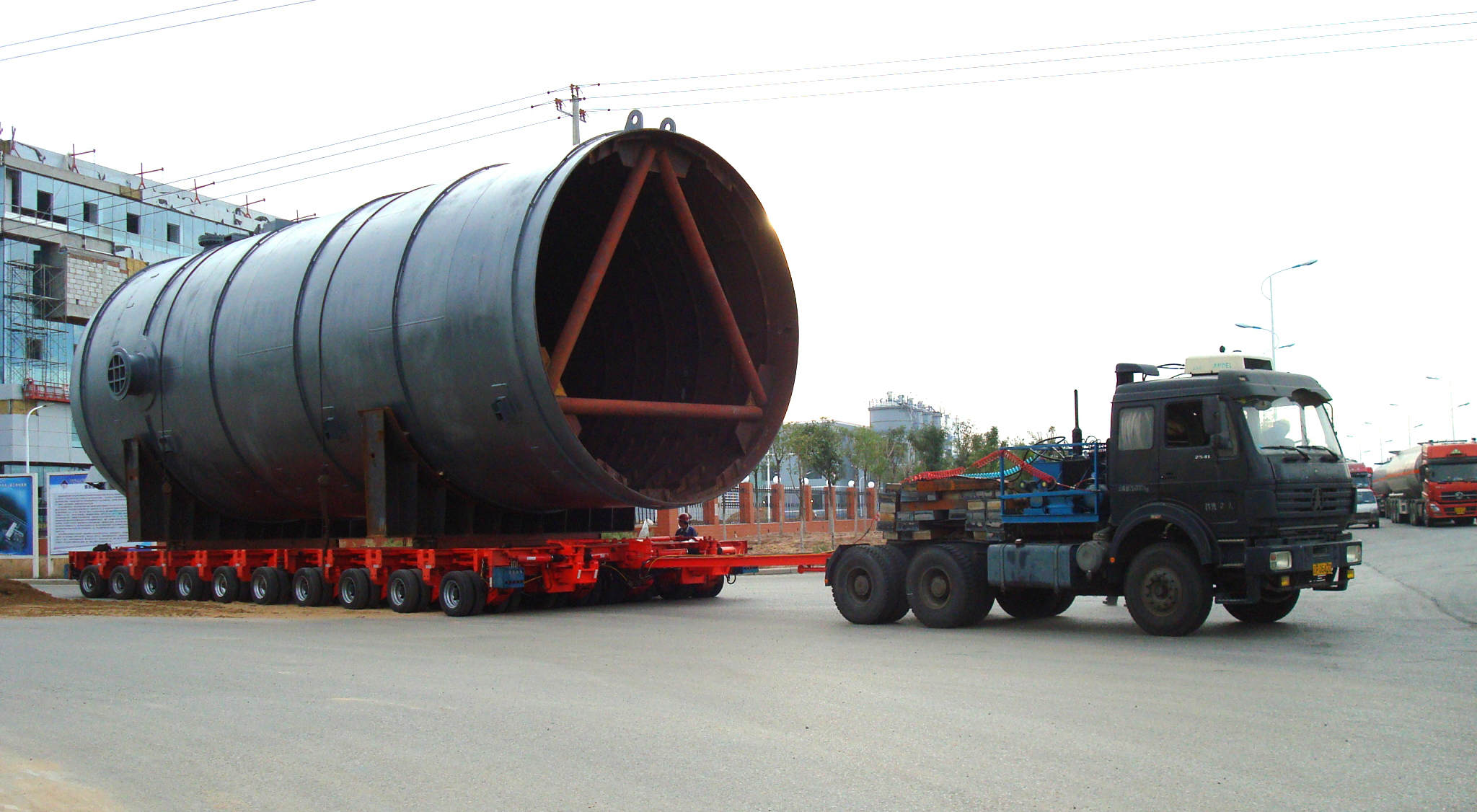 Multi-axle hydraulic modular trailer transporting oversized chemical vessel on highway