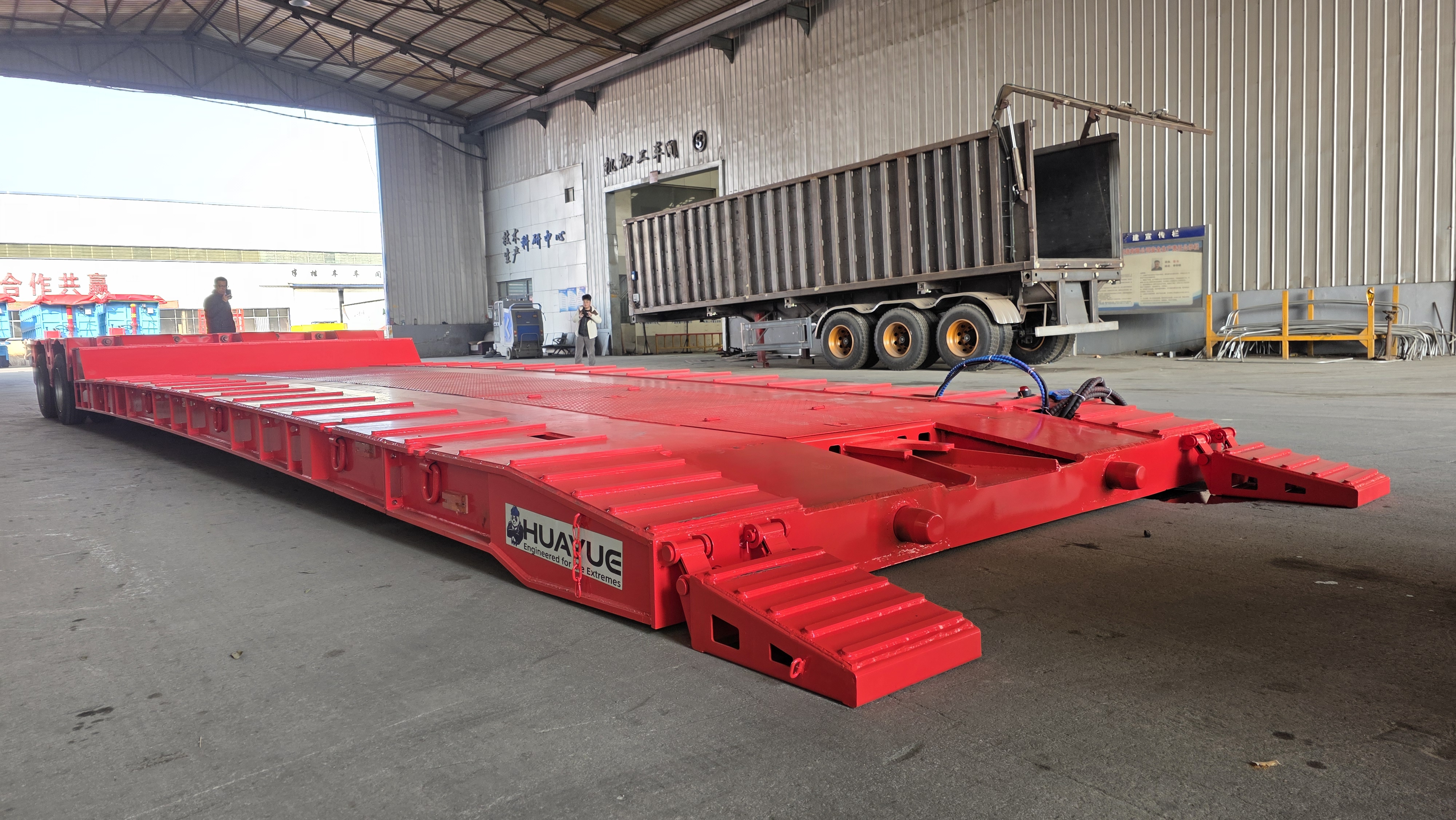 Close-up view of the detaching process of the front gooseneck section, showcasing the integrated ground ramp and the heavy-duty front climbing ladder for safe operator access