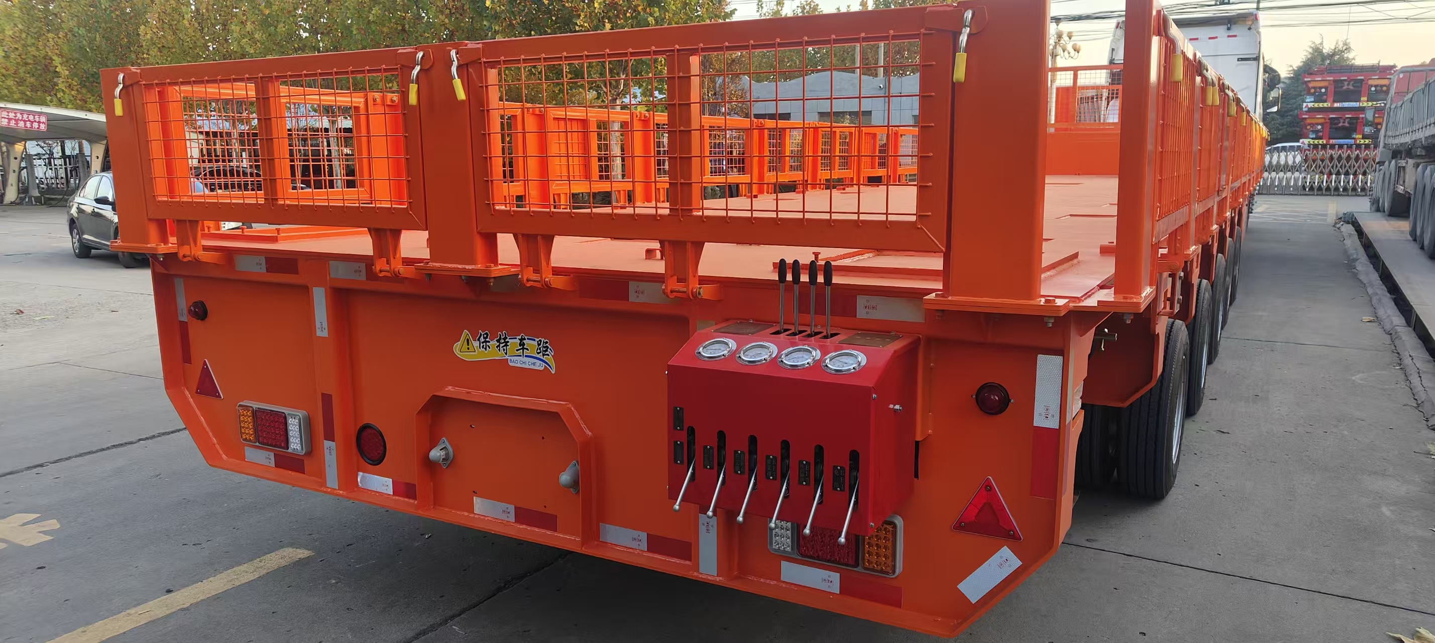 Rear view of the orange transformer transport trailer showing the protective fencing and a detailed rear control box with hydraulic levers and pressure gauges, prepared for a Saudi customer