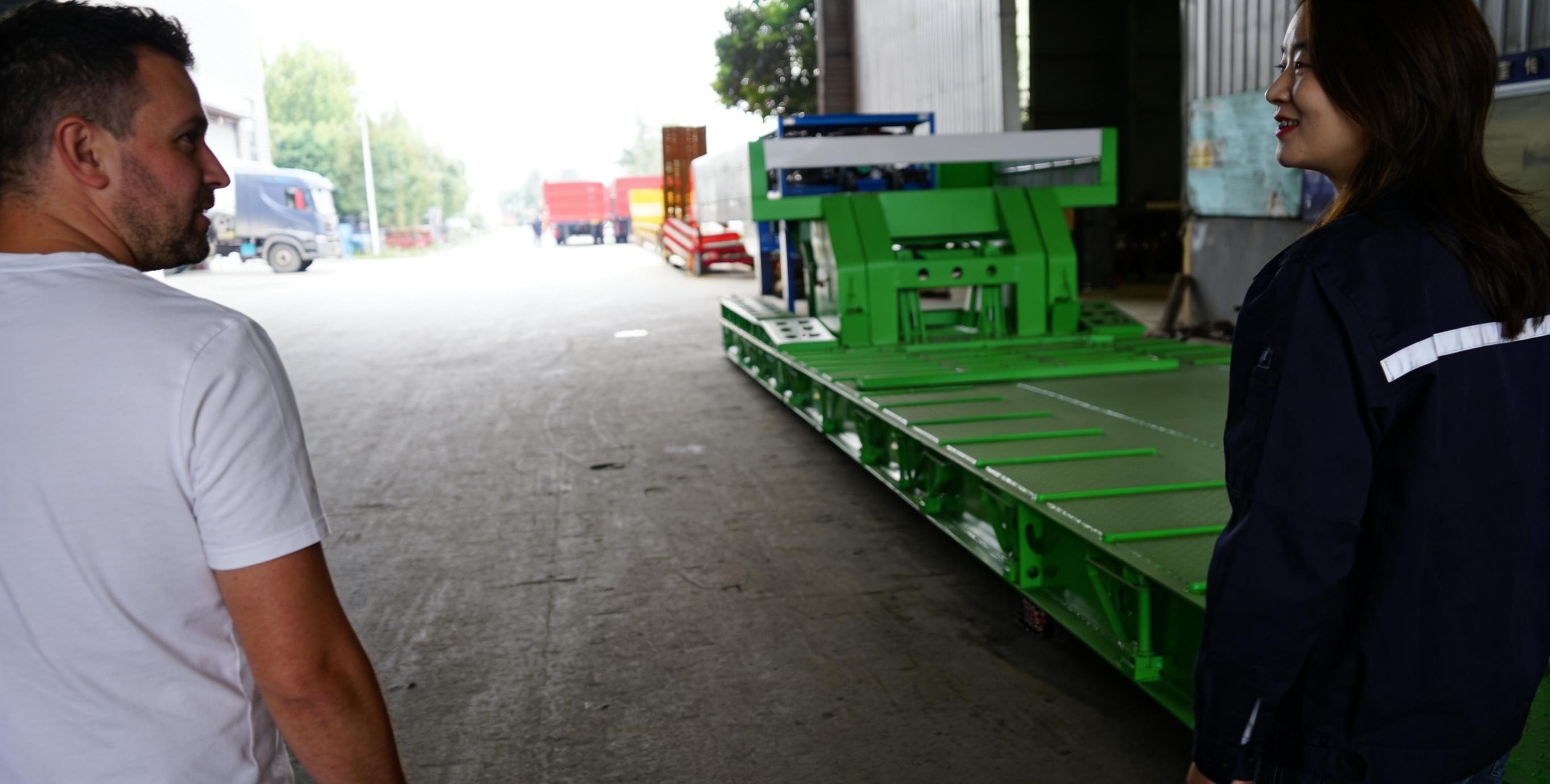 Malaysian customer inspecting the green HUAYUE 4 axle 100 ton removable gooseneck trailer during a factory visit