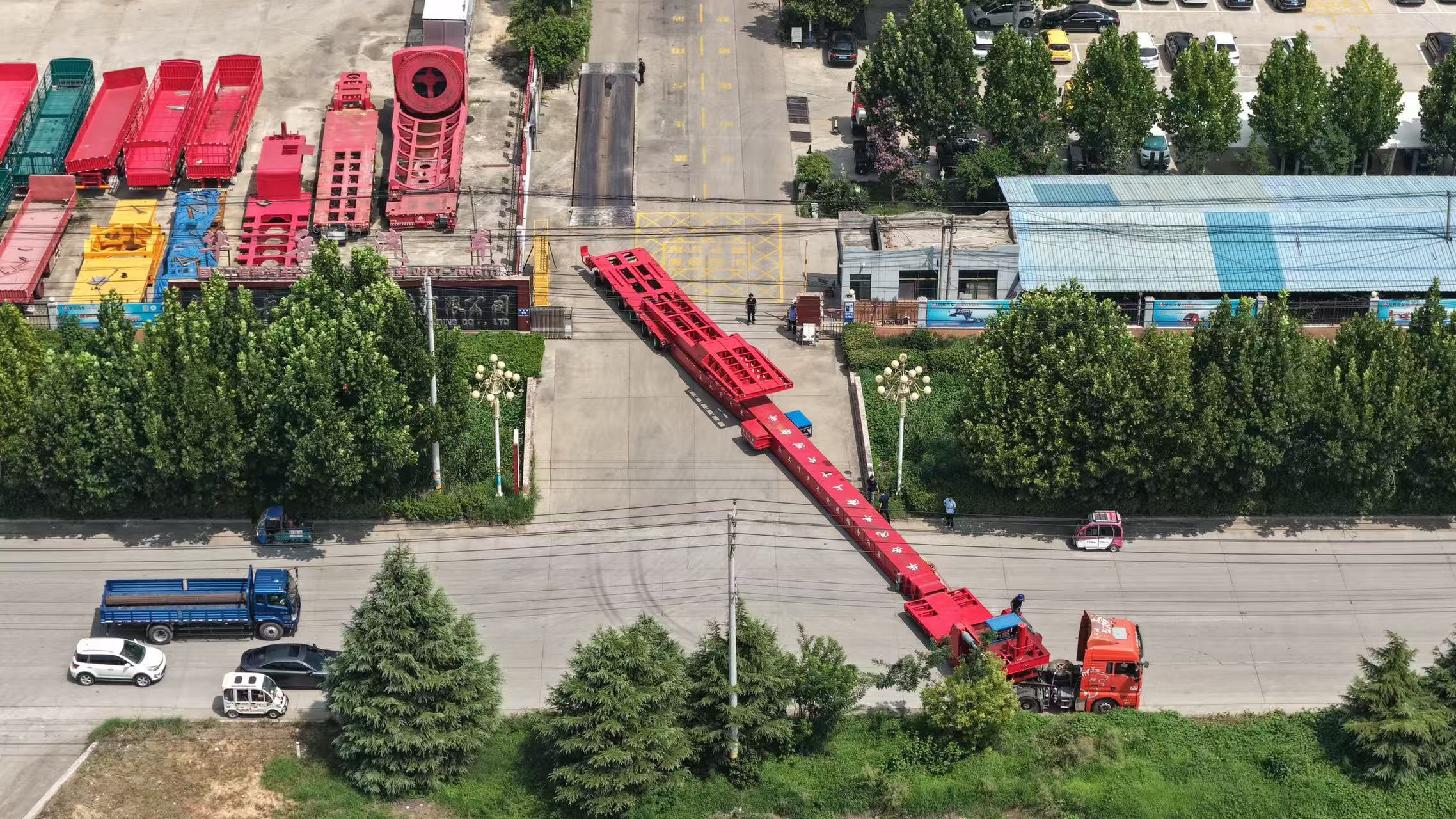 Close-up of the wind blade trailer's advanced rear steering axles actively navigating a sharp road curve while transporting a heavy blade