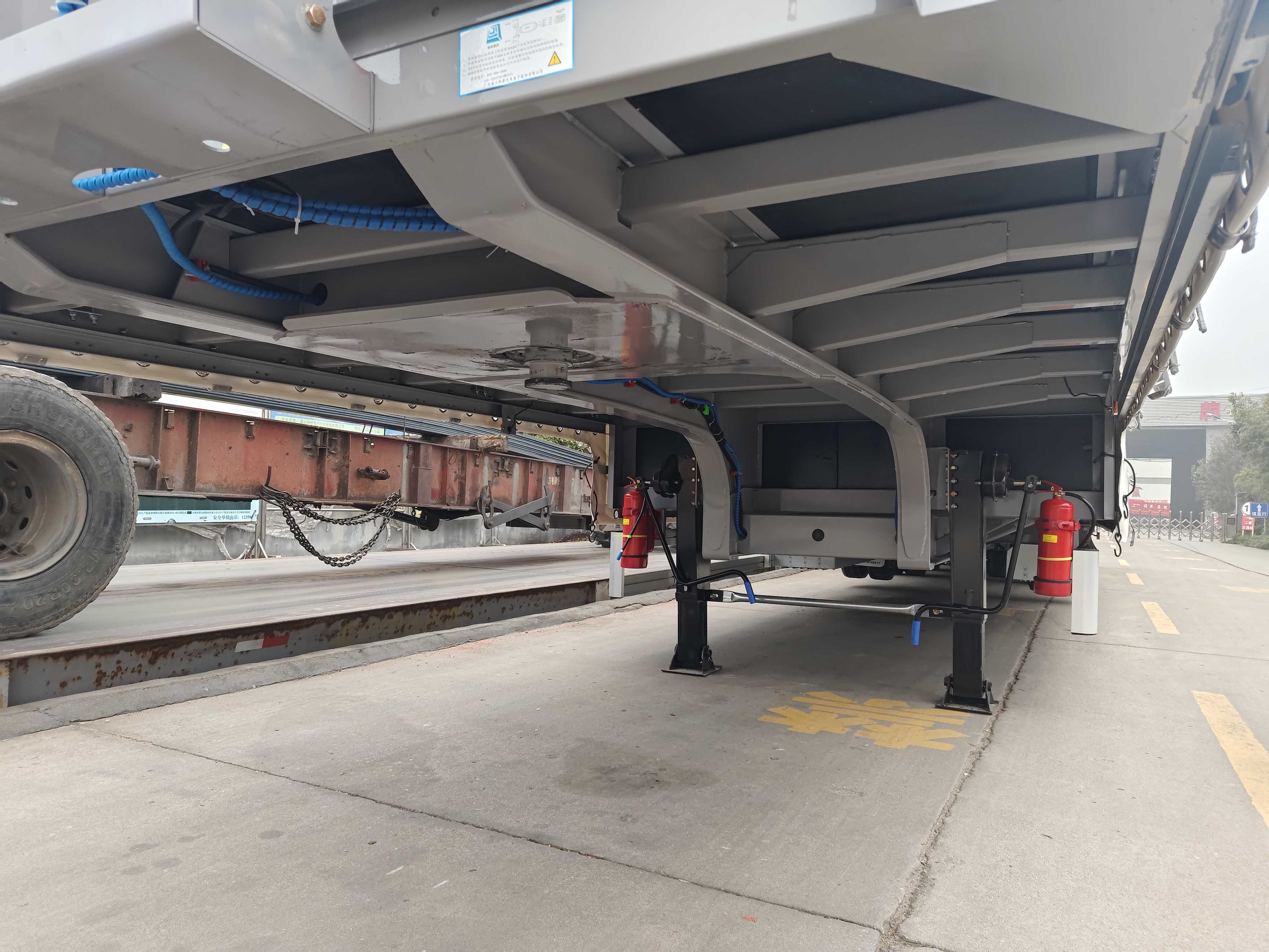 Detailed undercarriage view of the 3-axle curtain side trailer, highlighting the heavy-duty steel chassis, secure kingpin connection, and sturdy landing gear for safe transport