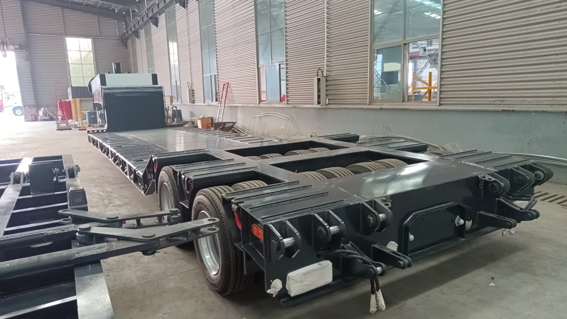 Detailed rear view of the HUAYUE lowbed trailer showcasing the heavy-duty folding hydraulic ramps and rear axle design engineered for safe and easy loading of construction equipment