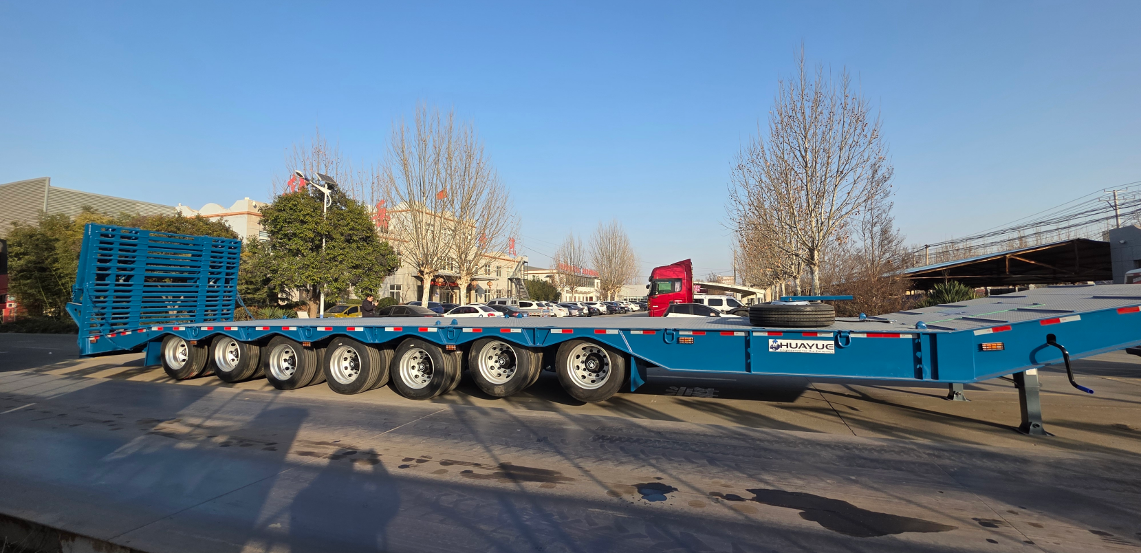 Full side view of an empty blue HUAYUE 7-axle lowboy trailer, showcasing its heavy-duty chassis and multi-axle configuration