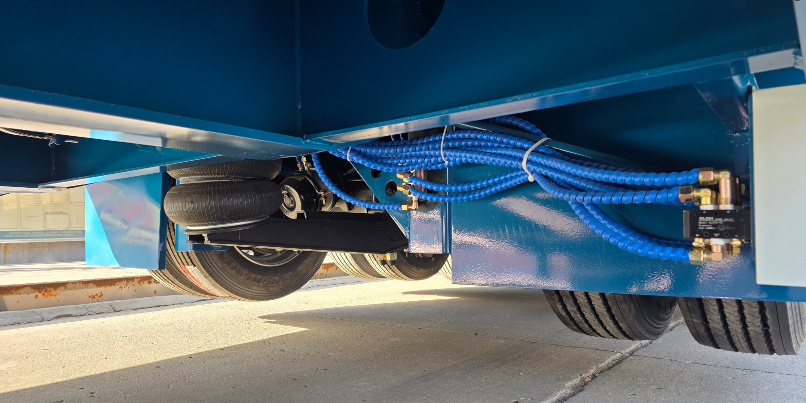 Close-up view of the HUAYUE trailer chassis underneath, featuring a robust air suspension system and precision control valves with routing lines