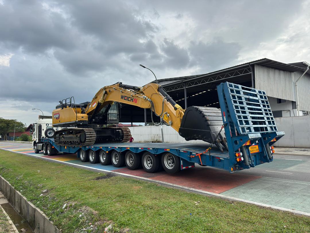 A HUAYUE 7-axle heavy trailer, having successfully obtained a JPJ permit and legal license plates, operating fully loaded with a large excavator on Malaysian roads