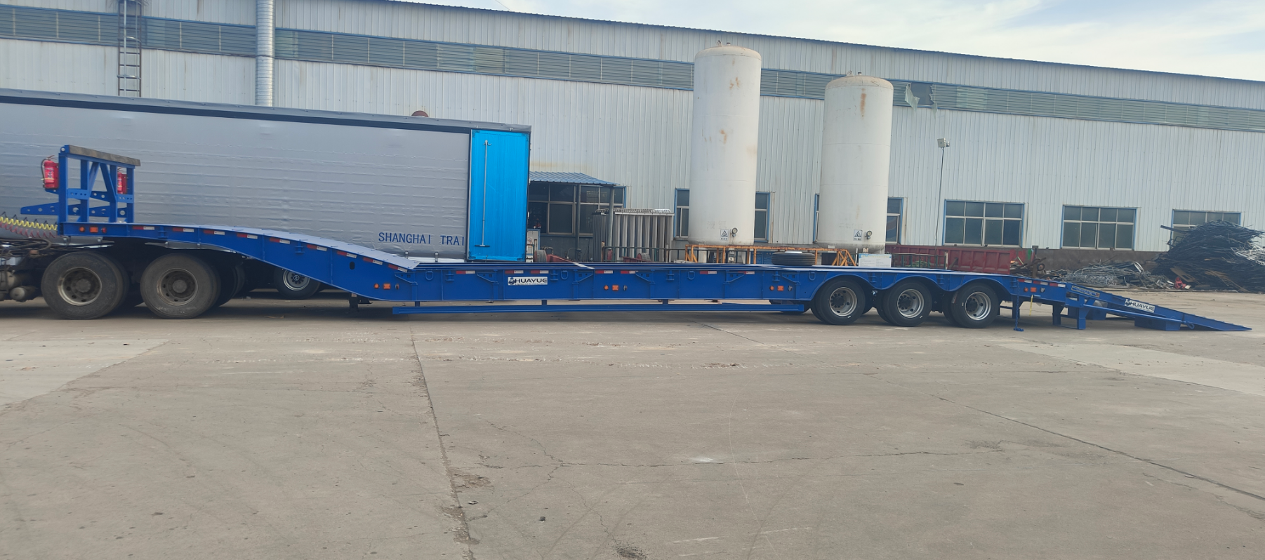 A panoramic side view of HUAYUE's custom 3-axle heavy-duty lowbed trailer, showcasing its ultra-low working platform and high-strength folding ramps.