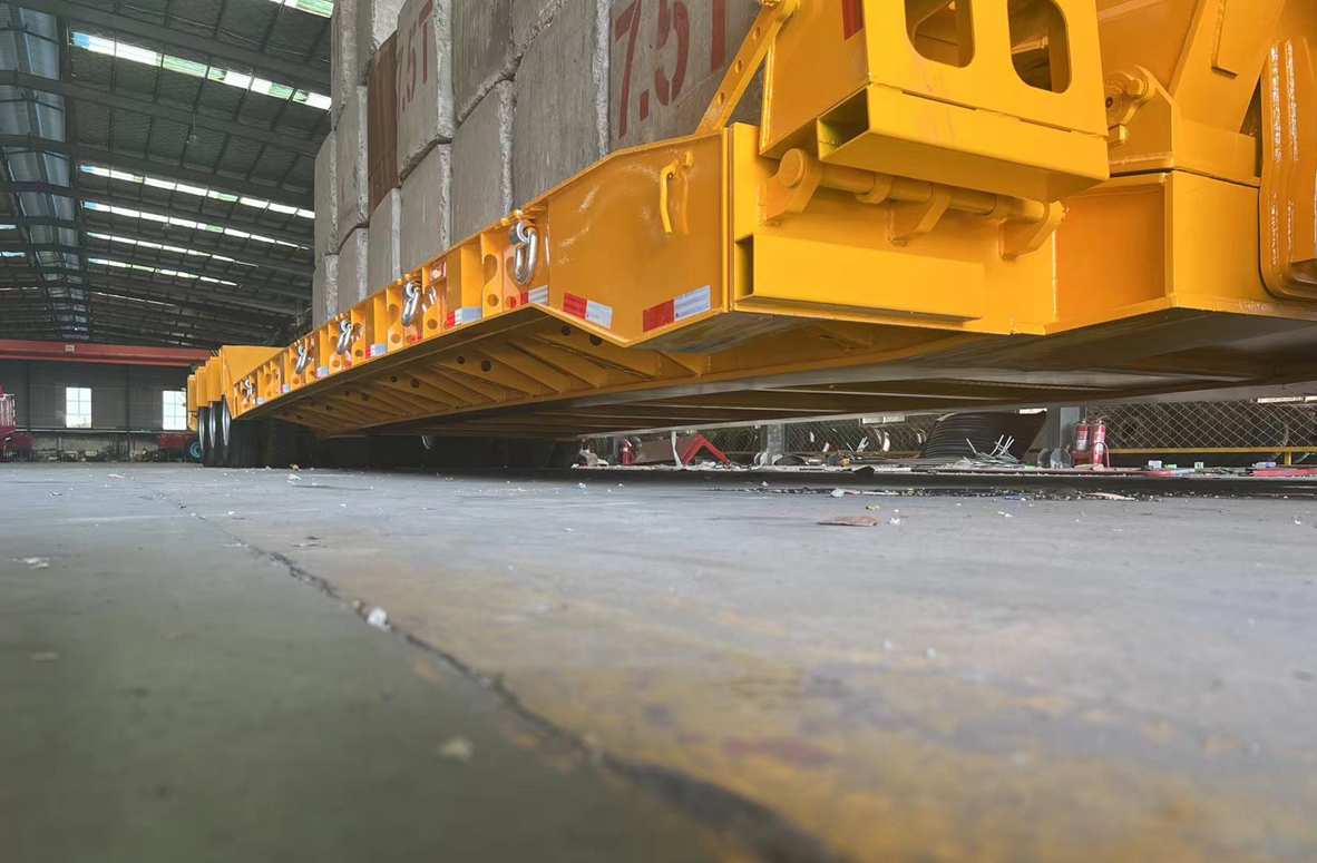 Bottom chassis view of HUAYUE 3-axle detachable gooseneck lowboy trailer, showcasing high-yield steel main beams and dense cross-member structure for extreme heavy haulage.