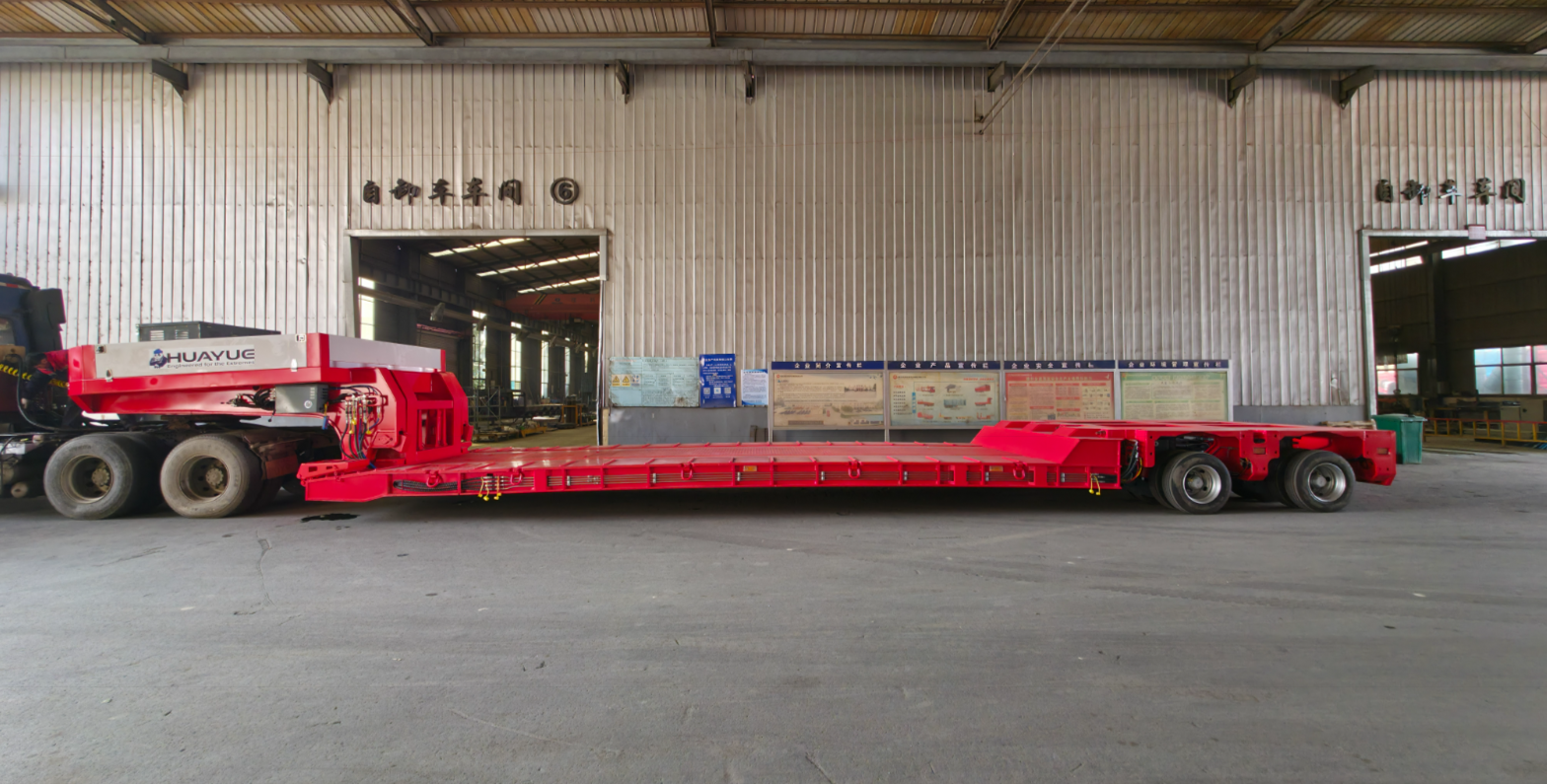 Side view of HUAYUE custom red hydraulic detachable gooseneck (RGN) lowboy trailer, featuring an ultra-low working platform and prominent brand logo, ready for heavy transport.