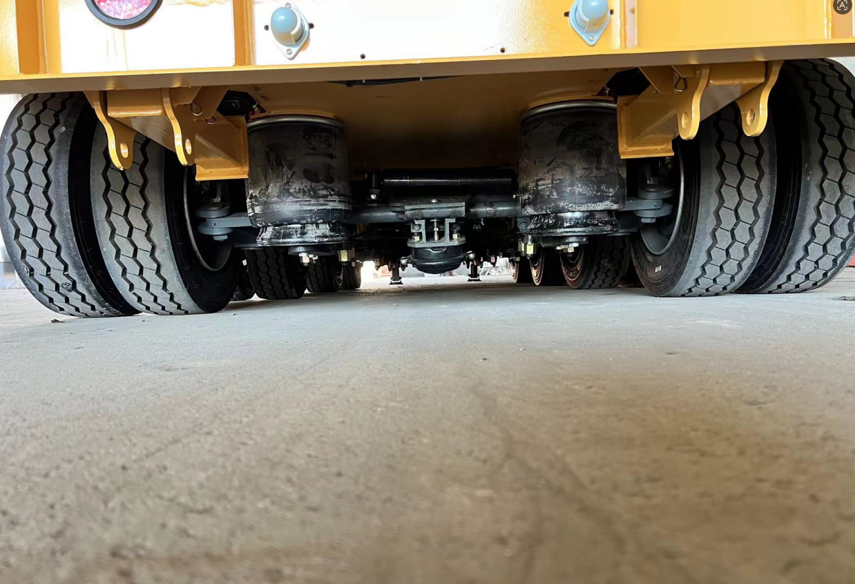 Under-chassis view of the HUAYUE European lowbed trailer, showcasing heavy-duty air suspension airbags engineered to absorb road shocks and protect sensitive, high-value cargo like transformers.
