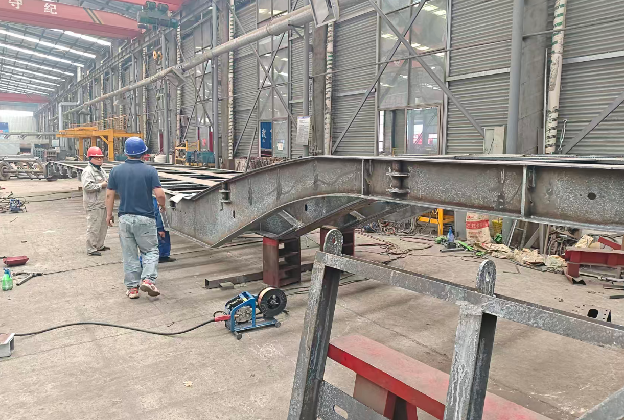 Fabrication of a heavy-duty lowbed trailer gooseneck section at the HUAYUE factory, highlighting the thick steel plates and reinforced transition curves.
