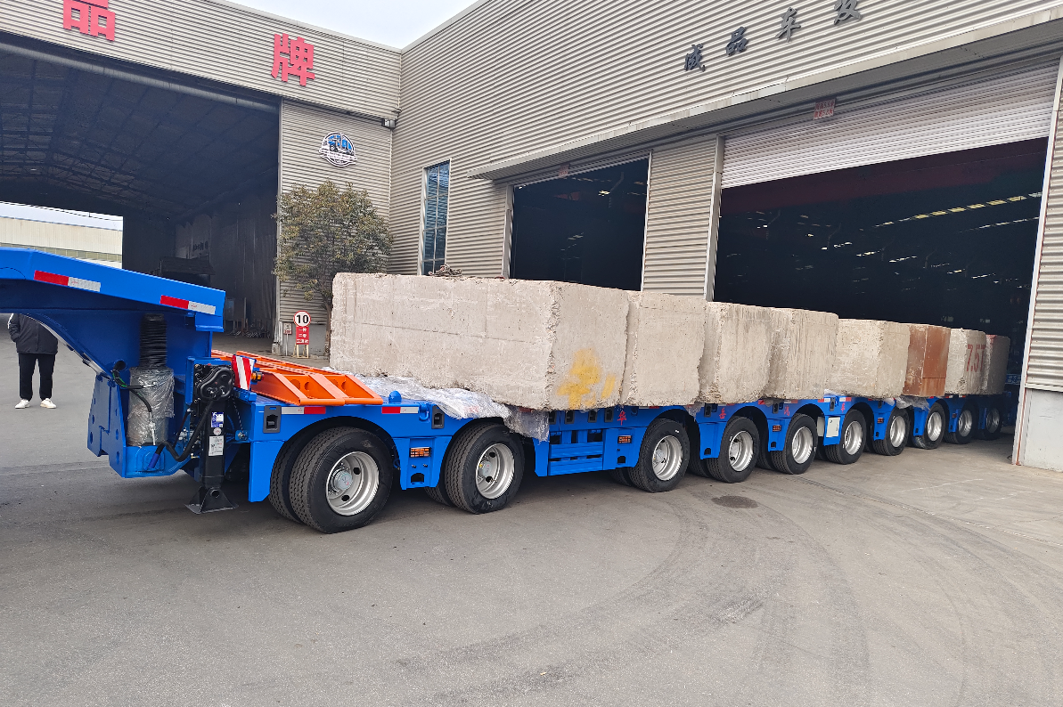 HUAYUE 10-axle extendable heavy-duty lowbed trailer undergoing a maximum payload test, demonstrating zero sagging of the central box-beam under a 100-ton concrete weight load.