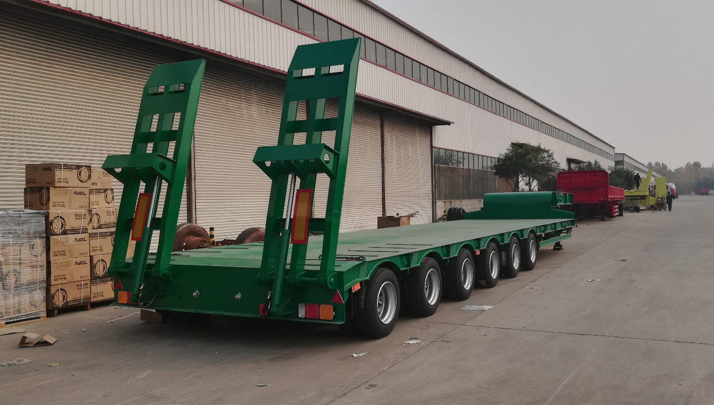 Rear close-up of the HUAYUE 6-axle lowbed trailer, showcasing the 20-ton heavy-duty hydraulic loading ramps and the 300mm side extension outriggers for wide machinery loading.