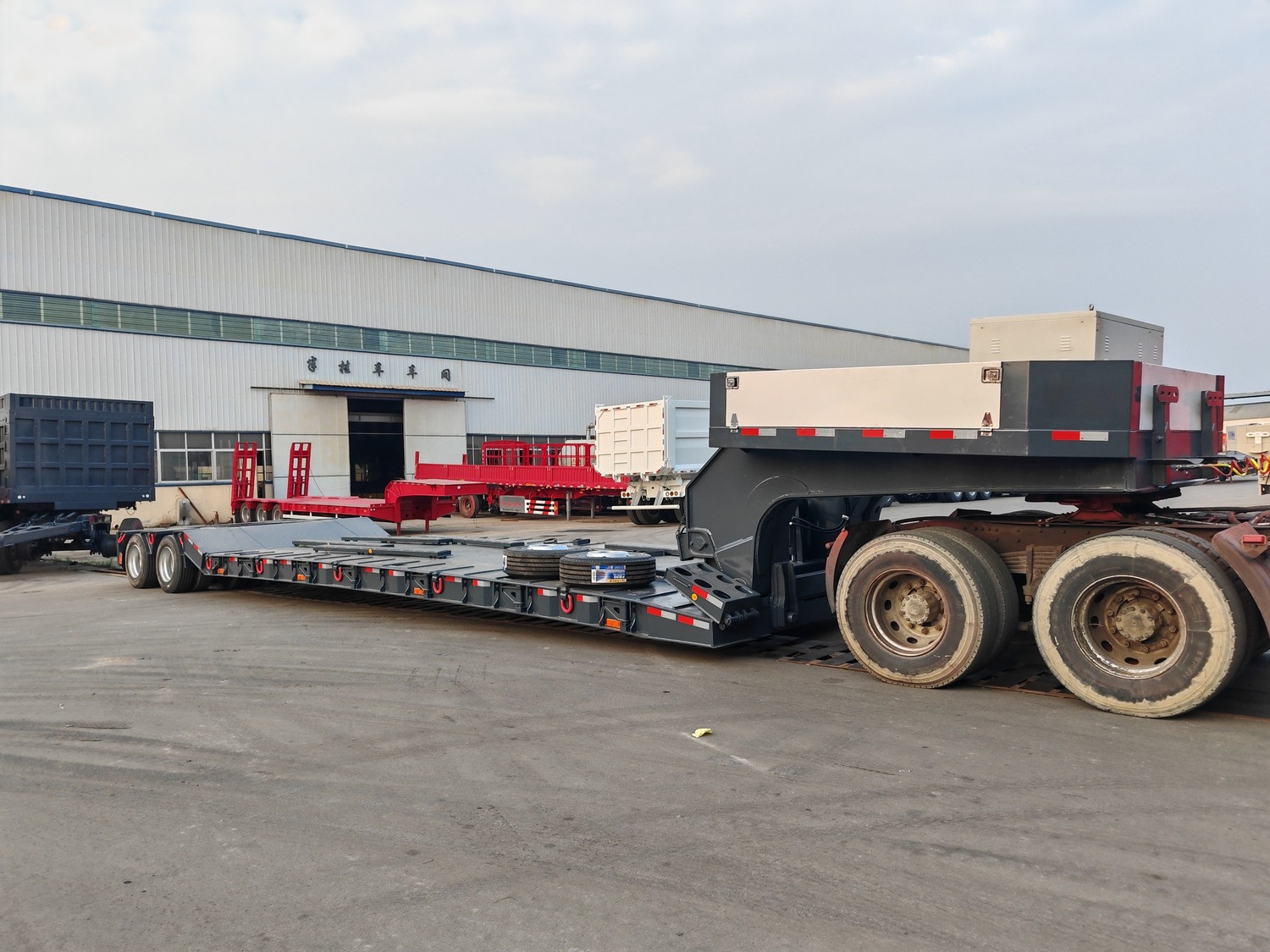 Detached removable gooseneck trailer deck positioned among trailers in a factory yard