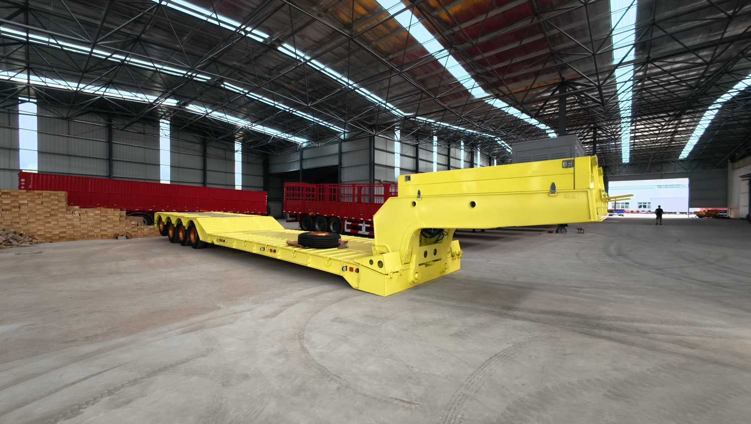 Yellow removable-gooseneck trailer sections arranged in a factory