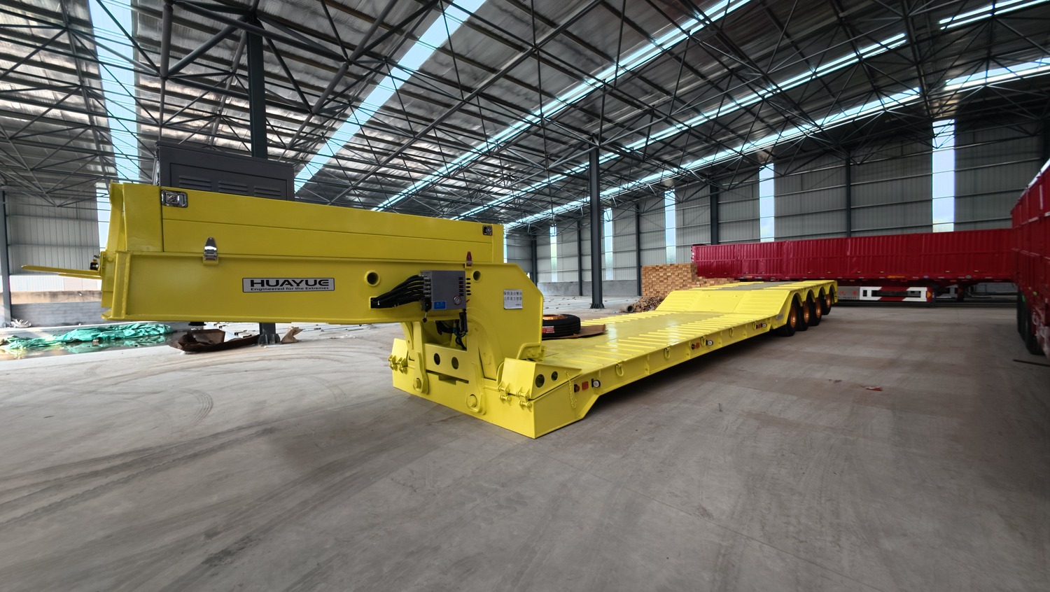 Yellow removable-gooseneck trailer frame and front connection area in a factory