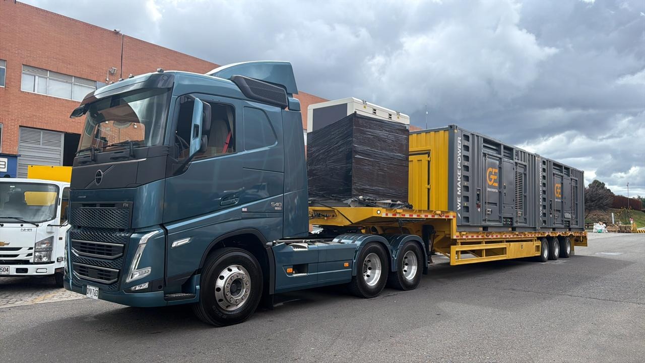 Yellow three-axle lowbed trailer coupled to a tractor with large equipment units on the deck