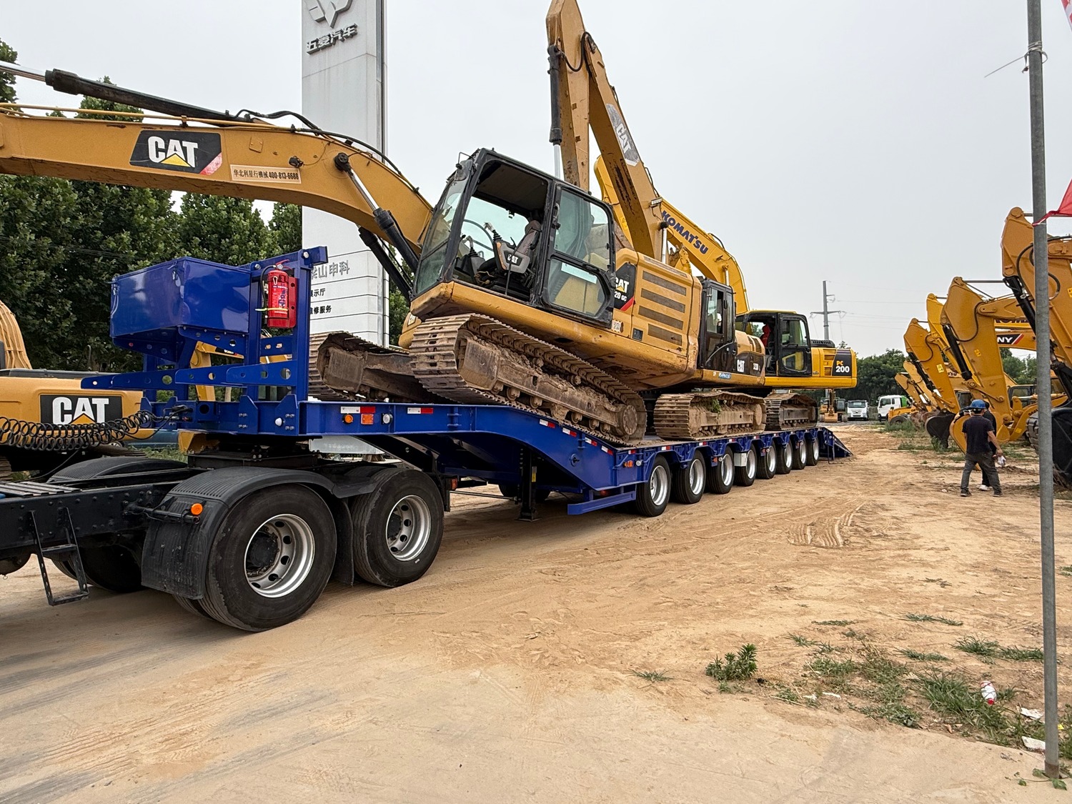 Excavator climbing the ramps of a HUAYUE lowbed trailer at a Malaysian work site