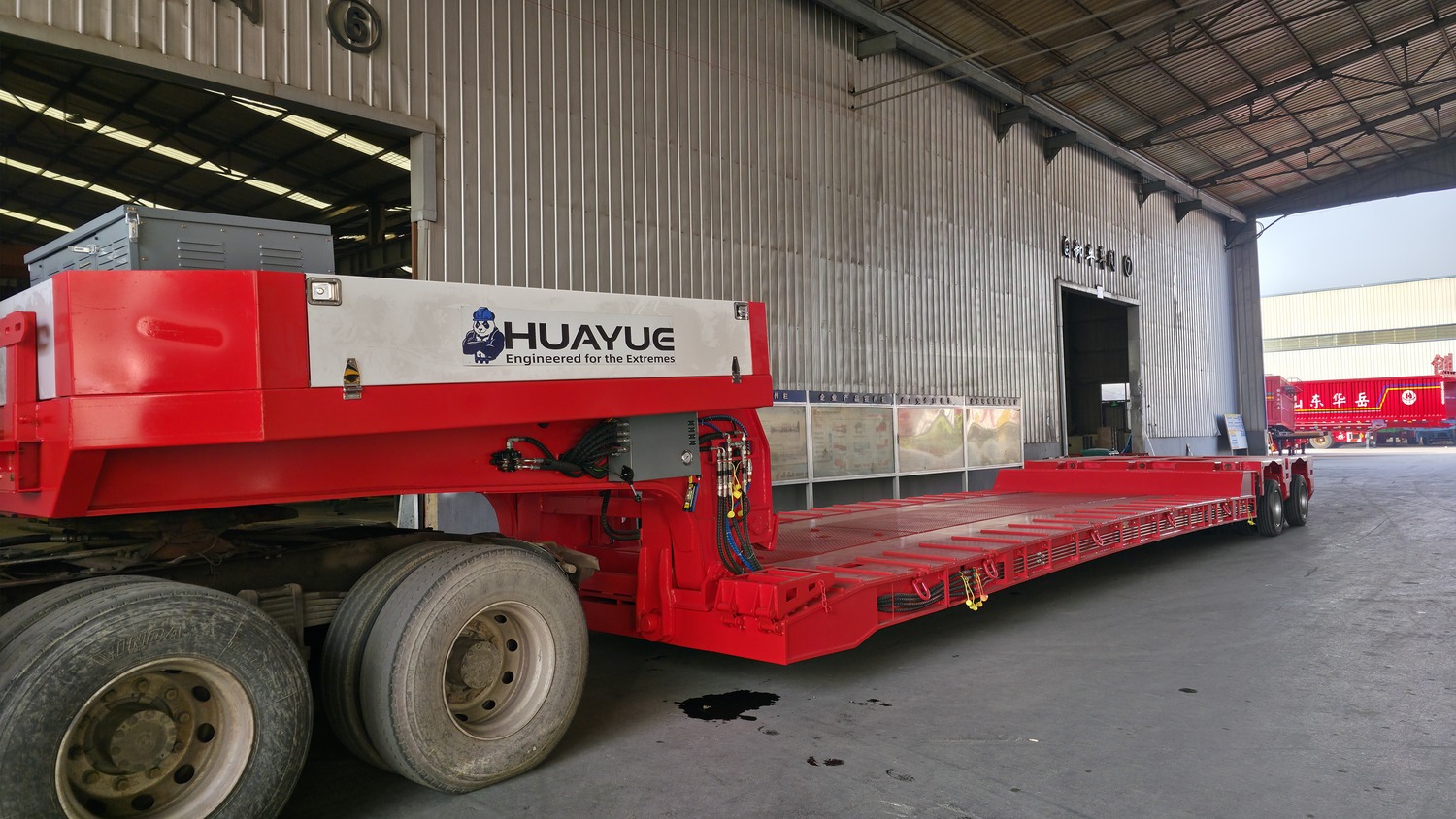 Red removable-gooseneck trailer with a long low deck visible at the Huayue factory