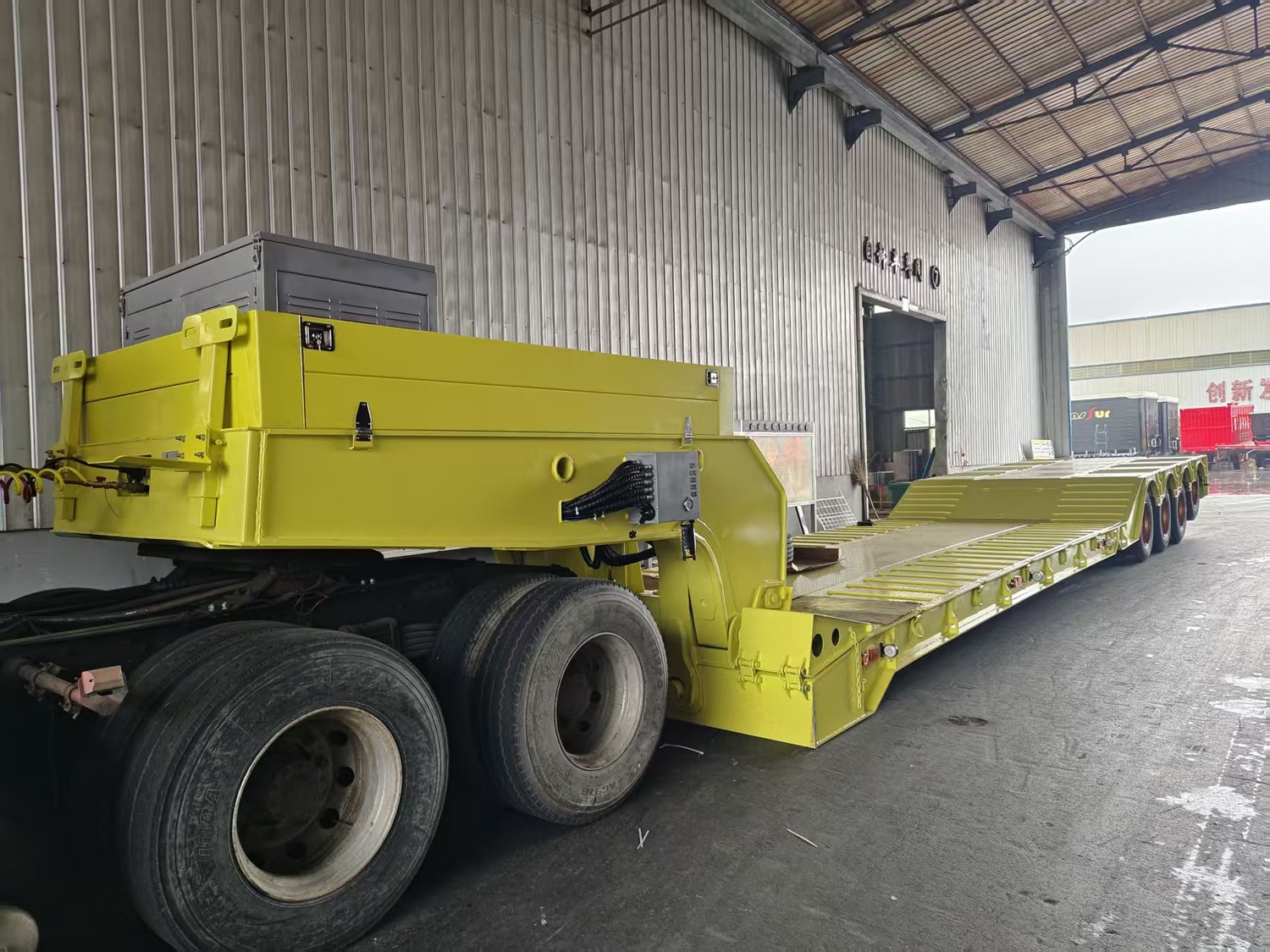 Yellow lowbed-style semi-trailer connected to a tractor at the Huayue factory