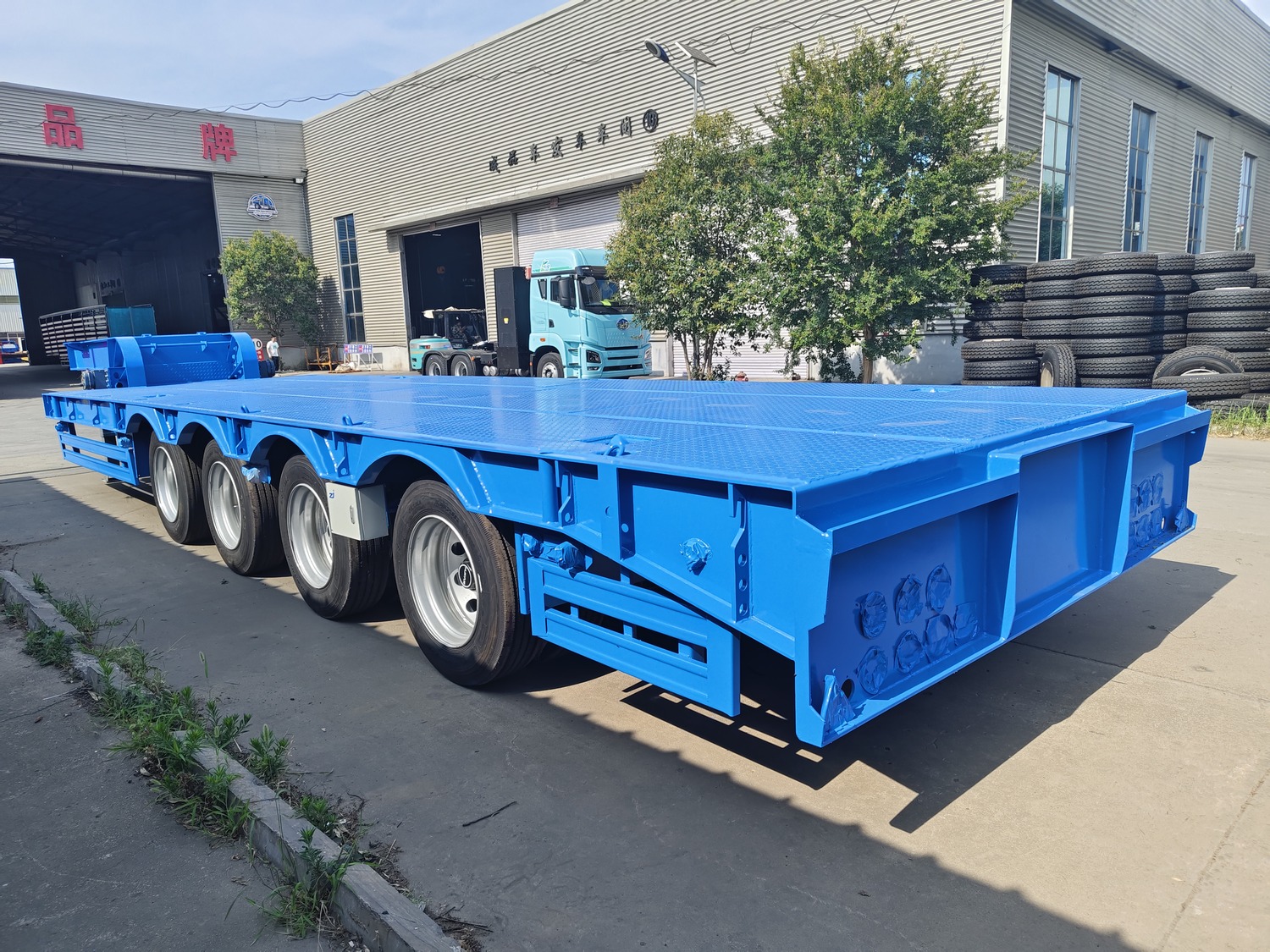 Blue lowbed semi-trailer reference vehicle with four axles and wide loading deck