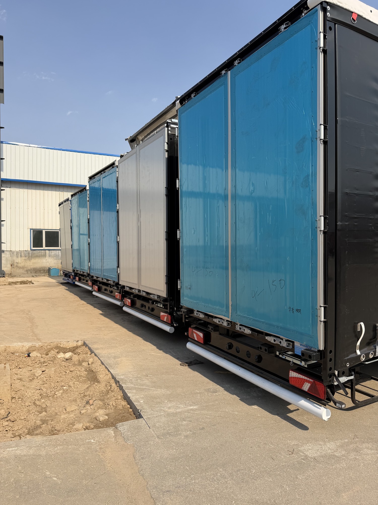 Rear views of curtain side semi-trailers with blue and silver curtain panels