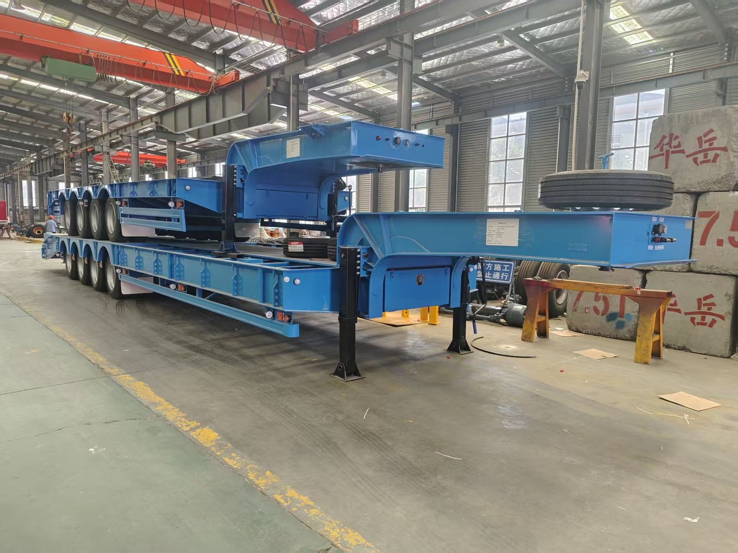 Blue 4-axle lowbed trailers with visible gooseneck sections arranged for export packing
