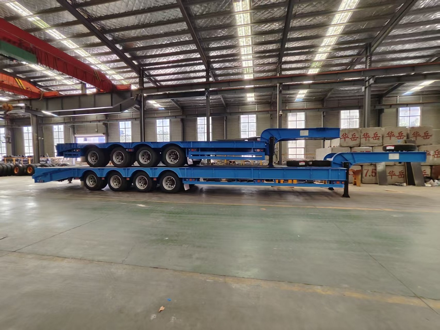 Standard and reverse-folding-ramp 4-axle lowbed trailers packed together in the workshop
